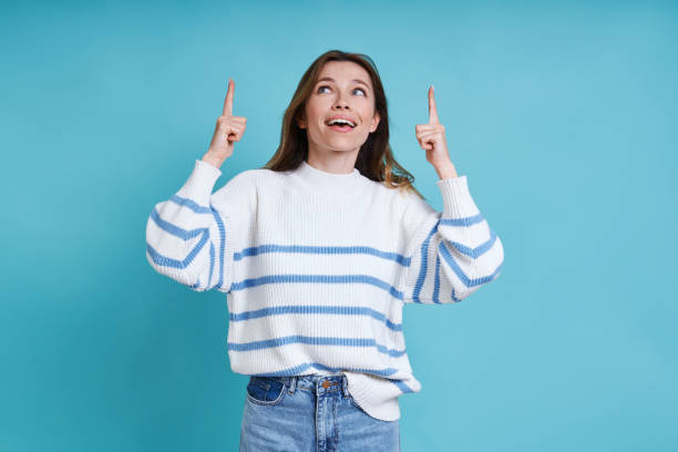 istock Beautiful young woman pointing up and smiling 1400144548