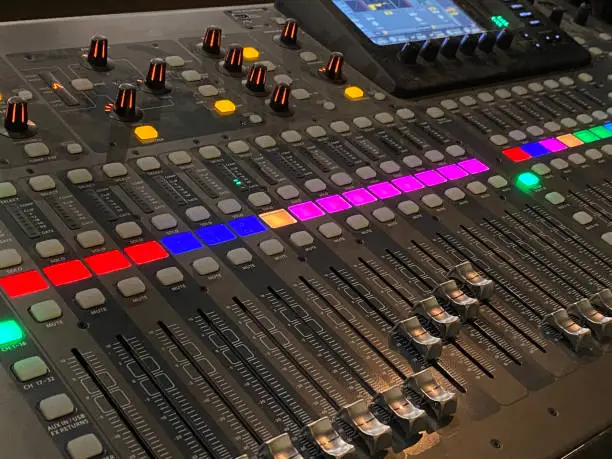 black sound board with red, blue, pink and green lights. Slider knobs to increase and decrease sound levels