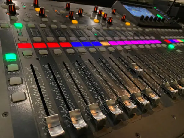 black soundboard with red, blue, pink and green lights. Slider knobs to increase and decrease sound levels