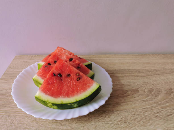 istock Pieces of sliced ​​watermelon with seeds on a white plate 1400147843