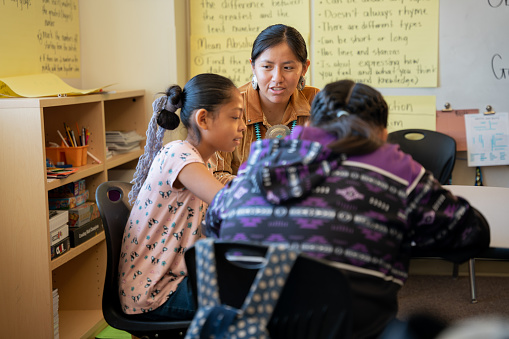 Young Female Indigenous Navajo Teacher Assisting Elementary Age Students in Class Room at an Elementary School in Monument Valley Utah