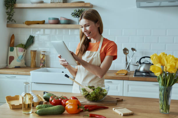 istock Happy young woman cooking and using digital tablet 1400148996