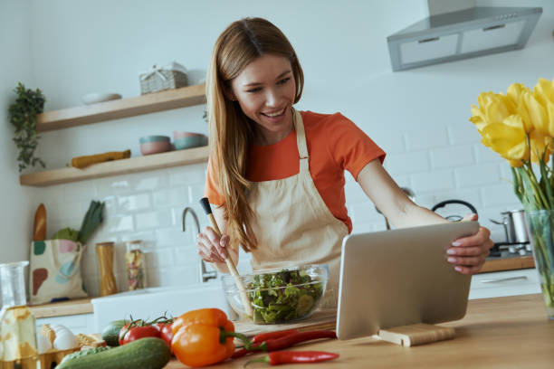 istock Confident young woman cooking and using digital tablet 1400148997