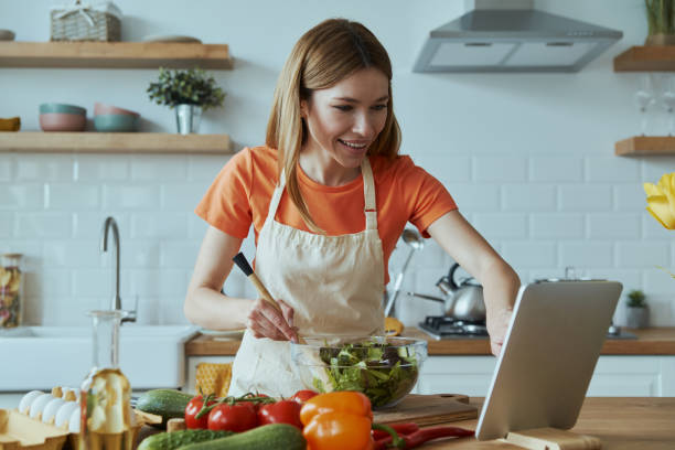 istock Confident young woman cooking and using digital tablet 1400149006
