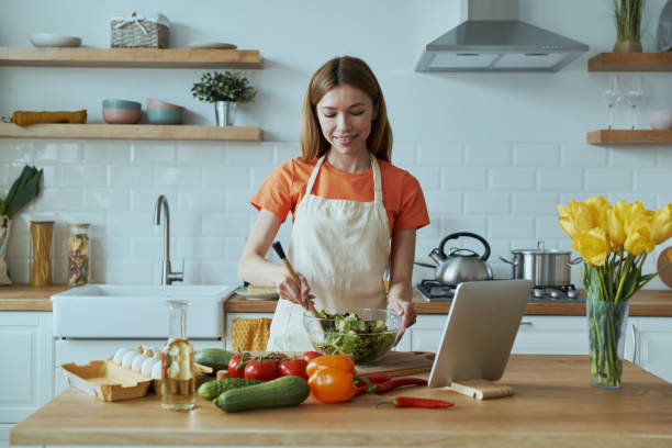 istock Beautiful young woman cooking and using digital tablet 1400149009