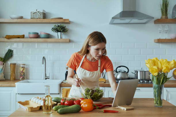 istock Concentrated young woman cooking and using digital tablet 1400149017