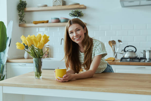 istock Cheerful young woman holding yellow cup and looking at camera 1400149080