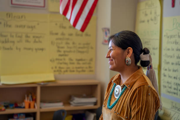 lächelnde junge lehrerin an der vorderseite ihres klassenzimmers, die ihre jungen schüler anspricht und unterrichtet - navajo american culture indigenous culture women stock-fotos und bilder