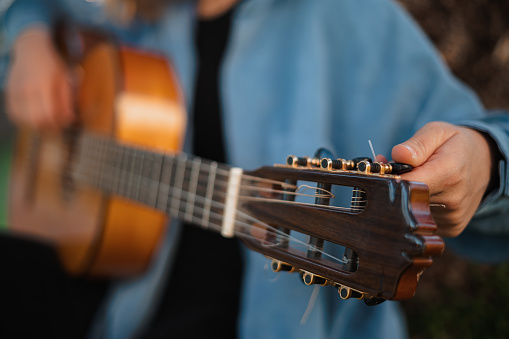 Close up of guitar peg while woman is tuning it