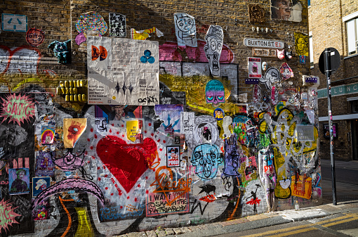Grafitti and street art on a wall in Buxtin Street off Brick Lane in London, UK.