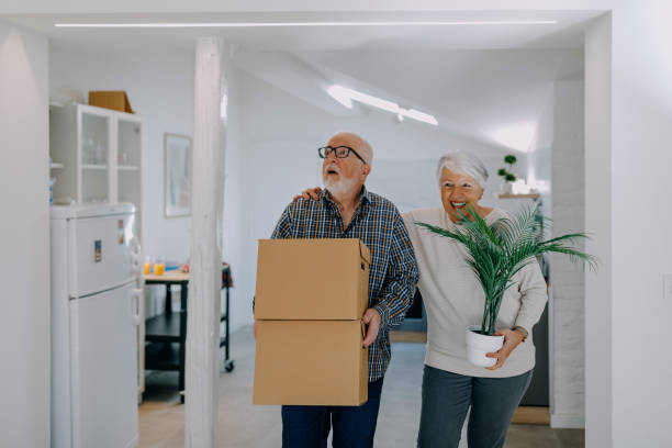 istock Senior couple smiling while carrying boxes into their new home 1400153479