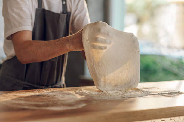 Kitchen chef preparing dough for pizza while working in a pizza place stock photo