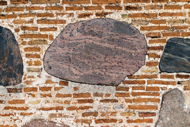 part of an old wall made of clay bricks and polished hewn stones stone brick wall of an old building, part of an old wall made of clay bricks and polished hewn stones roughhewn stock pictures, royalty-free photos & images