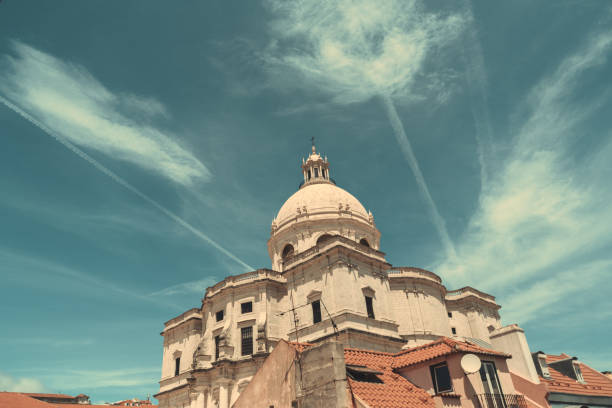 A wide-angle view of The Church of Santa Engracia or another name National Pantheon, with a cloudscape behind it and a few residential houses in the foreground on a warm sunny day, Lisbon, Portugal