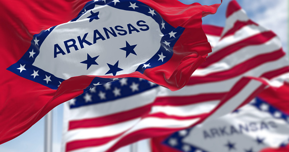 The flags of the Arkansas state and United States waving in the wind. Democracy and independence. US state flag
