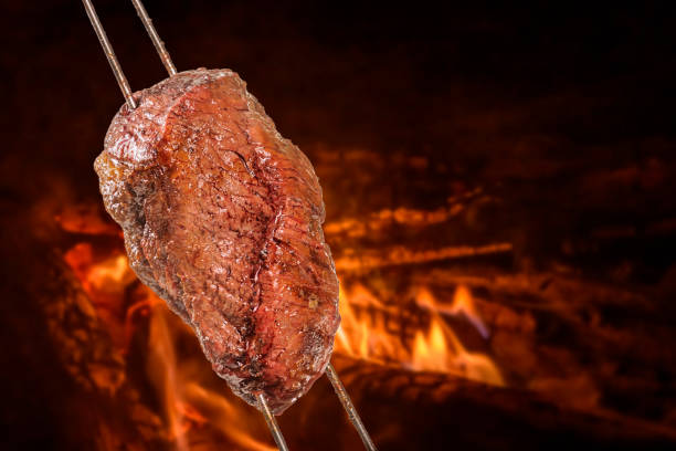 Barbecued Picanha barbecue with blurred fire in the background. Also called churrasco. stock photo