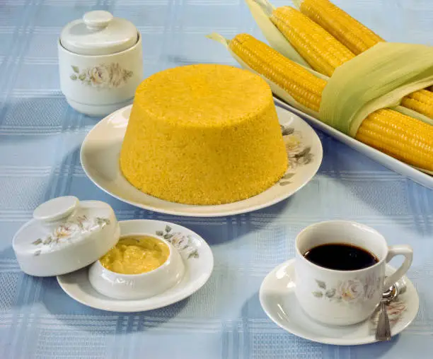 Corn couscous at the table with a cup of coffee and boiled corn cobs. Typical food from the northeast region of Brazil.