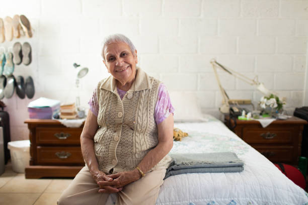 istock Senior woman sitting in her modest bedroom smiling 1400162811