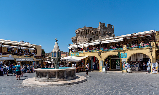 Rhodes Island, Greece - May 23, 2022: Tourists on the historic Hippocrates Square, in the Old Town center of the island of Rhodes, Greece. Hippocrates Fountain.