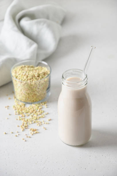 istock Green buckwheat milk in glass bottles on white table. 1400163911
