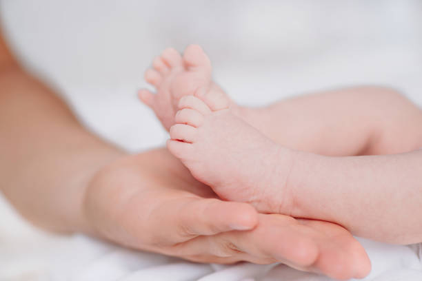 istock Soft newborn baby feet in dad's hands on a light background.Father's hand supporting the newborn's small feet.family child newborn love hand feet. Father and his child. Happy family concept. 1400164041