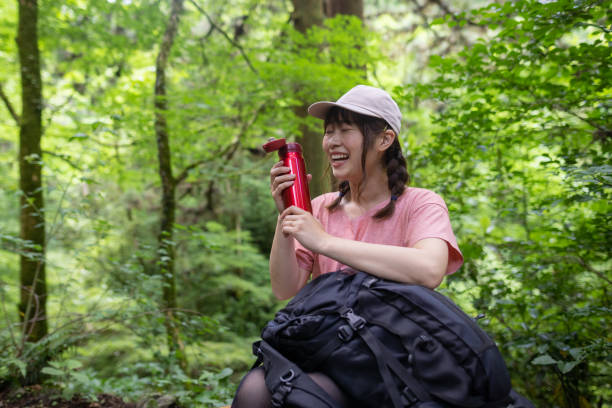 Woman satisfied with water, taking a break on the way to the mountain peak Japanese woman visiting Mt. Takao for hiking, and walking up to the peak. olive green shirt stock pictures, royalty-free photos & images