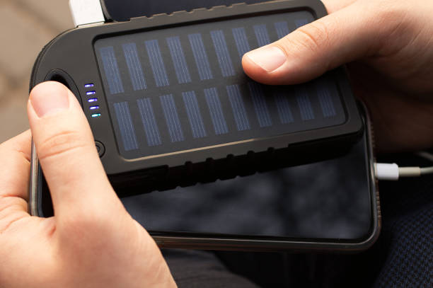 close-up fotografia da mão do homem, segurando powerbank com bateria solar e carregar telefone celular. - elecronic - fotografias e filmes do acervo