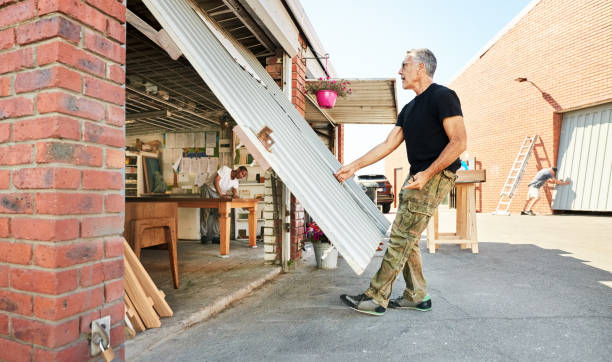 Senior man opening carpentry workshop door with a worker working inside on old furniture