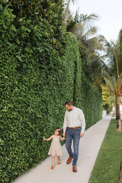 31-year-old american father walking down a sidewalk with his 3-year-old daughter while holding hands in palm beach, florida in the spring of 2022 - hedge multi ethnic group people holding hands imagens e fotografias de stock