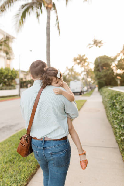 31-year-old american father walking while holding his 3-year-old daughter while having her head on his shoulder in palm beach, florida in the spring of 2022 - hedge multi ethnic group people holding hands imagens e fotografias de stock