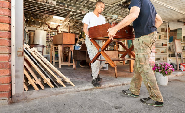 istock Two carpenters carrying wooden table outside workshop for delivery 1400177379