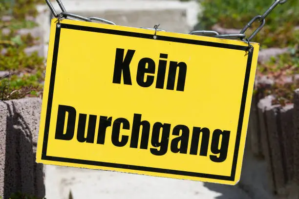 yellow sign on a closed footpath in Germany. Translation: no passage
