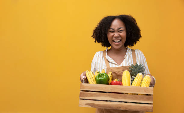 consegna felice da donna afroamericana che trasporta un carrello pieno di prodotti biologici tropicali coltivati in casa dall'orto locale per ingredienti vegani e vegetariani - agriculture food vegetable fruit foto e immagini stock