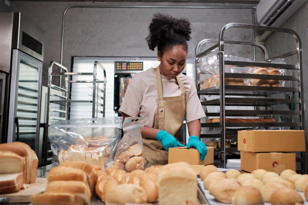 Female cook is packing handmade and fresh-baked bread for online customers. stock photo