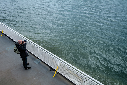 Gulf Islands, British Columbia, Canada - May 27, 2022:  Photographer photographing off the side of a BC Ferry.