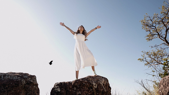 Beautiful woman stretching out her arms on a peak over the mountains.