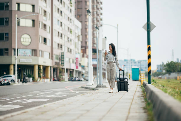 jovem empresária com mala olhando para o smartphone - urban scene business travel travel asia - fotografias e filmes do acervo