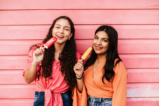 portrait of friends latin women eating a popsicle.