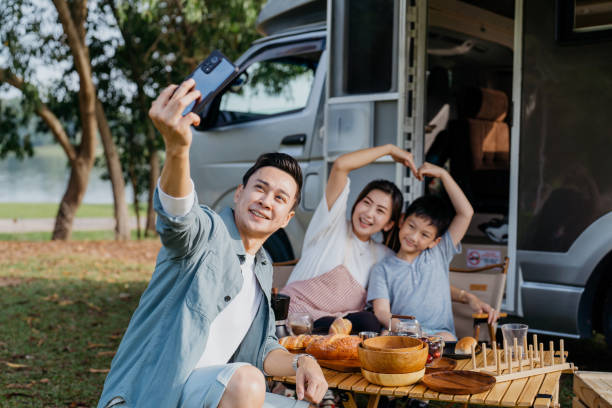 famiglia asiatica che scatta foto selfie durante la vacanza in roulotte picnic - car family picnic vacations foto e immagini stock