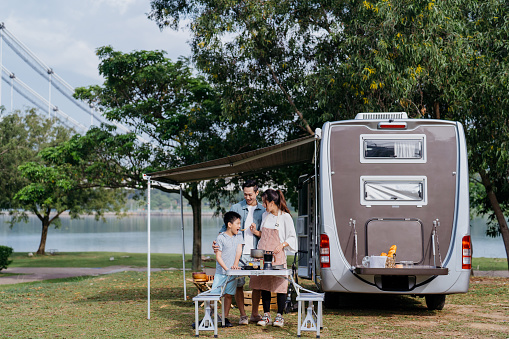 Image of an Asian Chinese family preparing food together during a caravan picnic vacation at public park