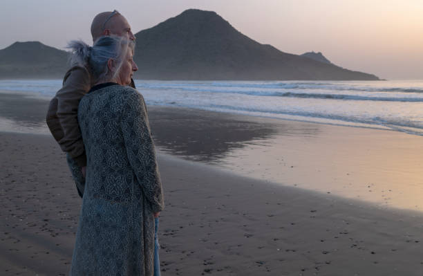 istock Senior couple standing on beach during sunrise 1400195742