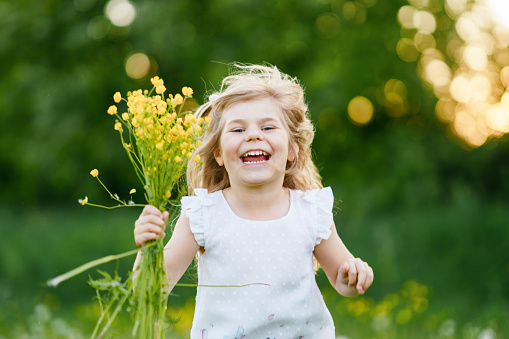 Cute charming little girl playing in the summer field