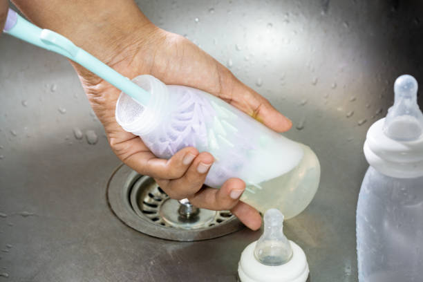 The mother cleans the baby's bottle using a bottle cleaner and uses a bottle-washing device to rotate it. The mother cleans the baby's bottle using a bottle cleaner and uses a bottle-washing device to rotate it. methodist stock pictures, royalty-free photos & images