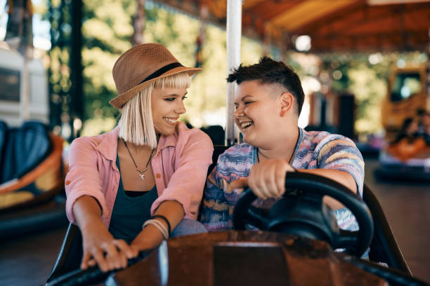 istock Happy lesbian couple talking while driving bumper car at amusement park. 1400200367