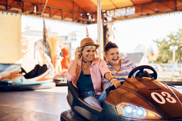 istock Cheerful lesbians having fun while driving bumper car at amusement park. 1400200386