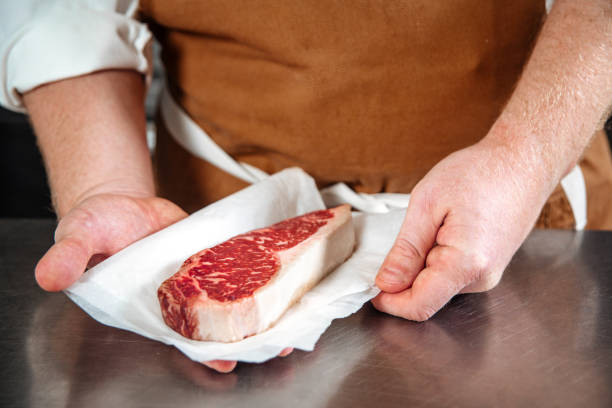 istock Chef holding raw beef steak in a parchment paper 1400207260