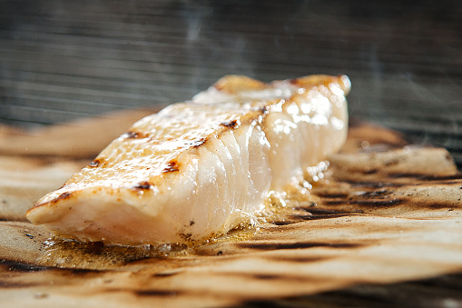 Closeup on grilling white fish fillet on the parchment paper