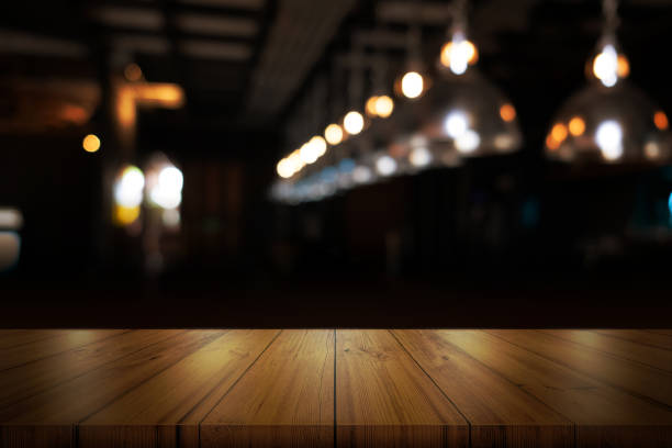 Empty wooden table top with blurred coffee shop or restaurant interior background.