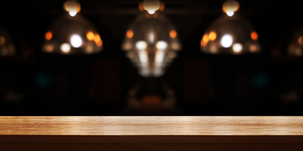 Empty wooden table top with blur coffee shop or restaurant interior background, Panoramic banner. Abstract background can be used for display or montage your products.