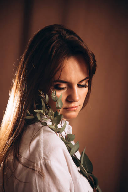 istock A girl with a beautiful make-up looks down holding eucalyptus branches in her hands 1400209613